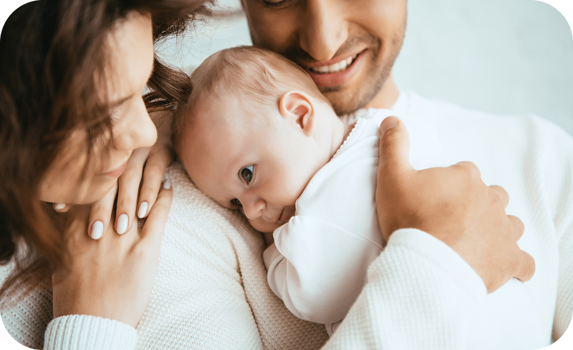 Una madre e un padre sorridenti abbracciano il loro neonato, trasmettendo amore e protezione.
